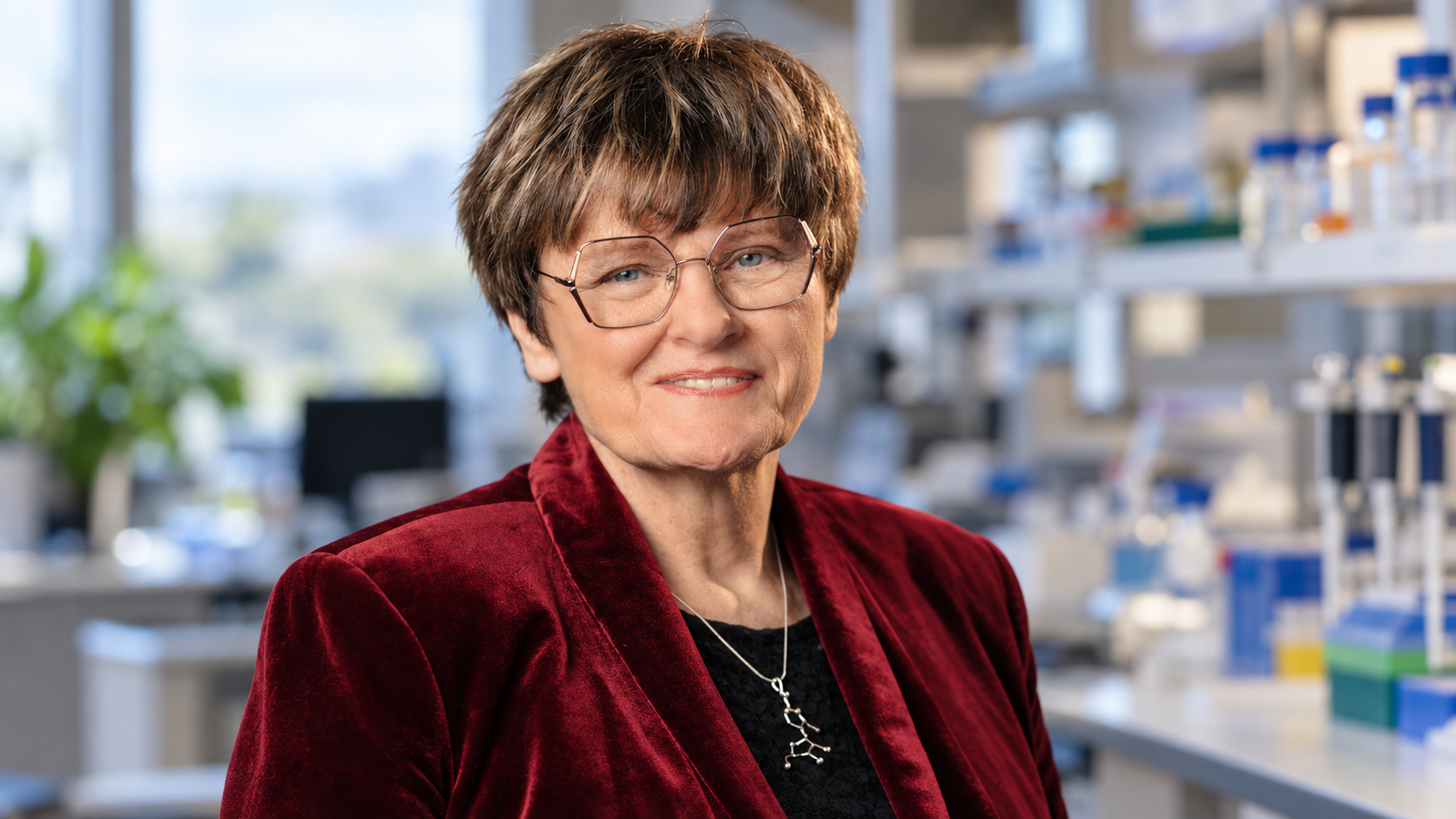 AI-generated realistic portrait of Katalin Karikó in an RNA research office.