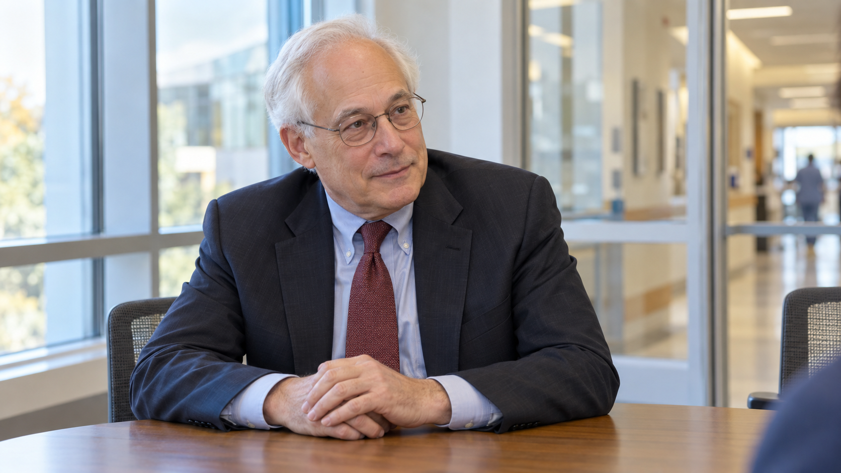 AI-generated realistic portrait of Donald Berwick in a recreated 2013 hospital education meeting room.