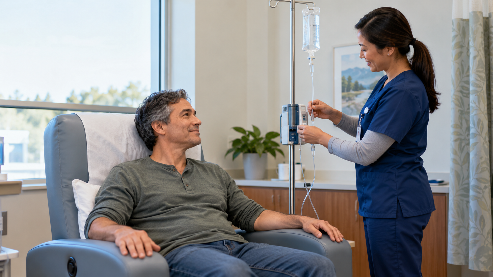 A nurse checks an IV setup beside an adult seated in a padded treatment chair in an infusion room.