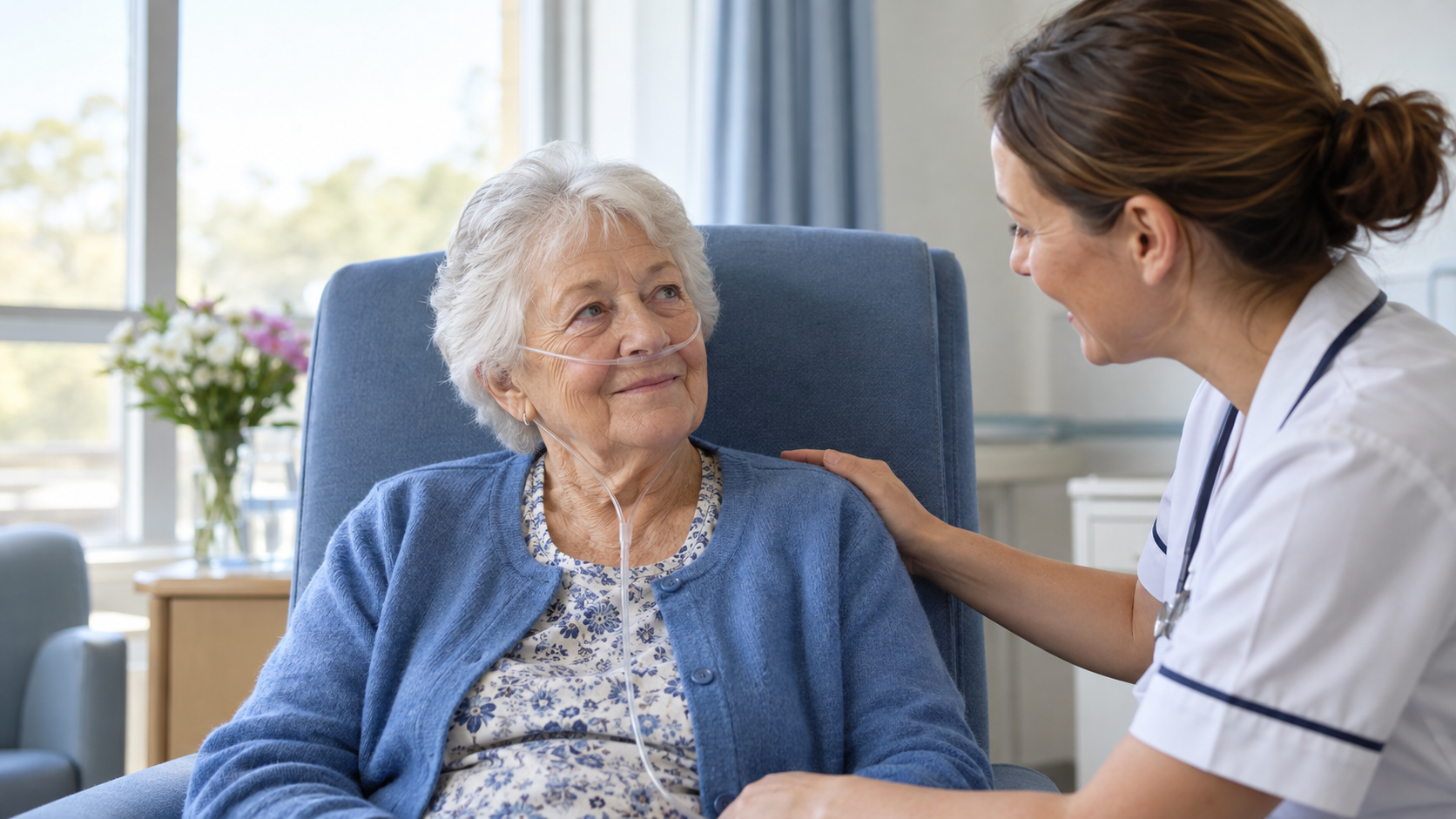 An older adult sits upright with a nasal oxygen cannula while a clinician offers reassurance.