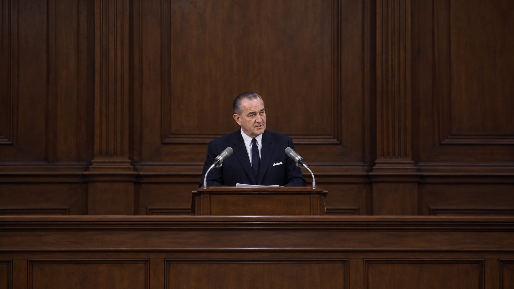 Historical reconstruction of Lyndon Johnson addressing Congress about voting rights at a wooden lectern in 1965.