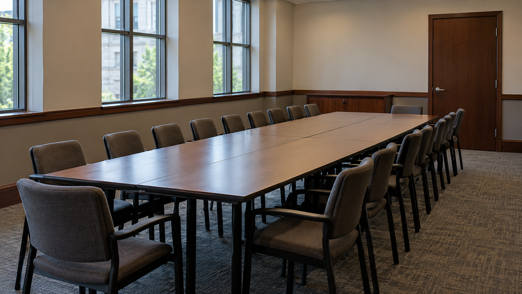 A plain jury meeting room with long tables, empty chairs, and a closed door