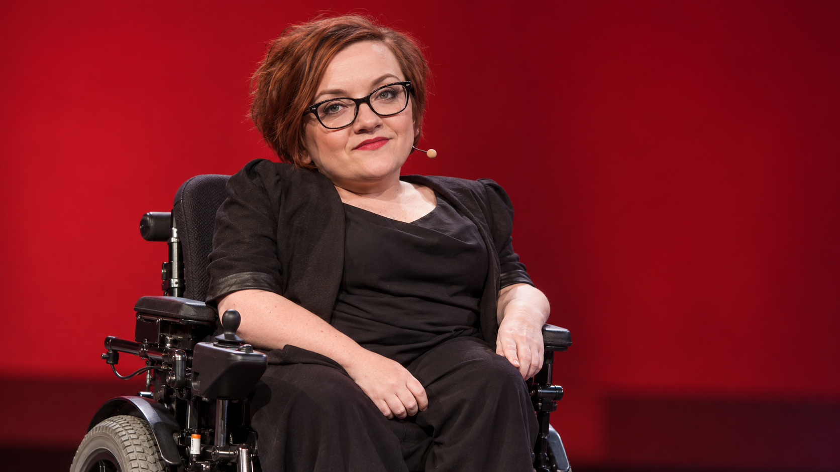 Stella Young in a contemporary stage with a simple red backdrop and no readable signage