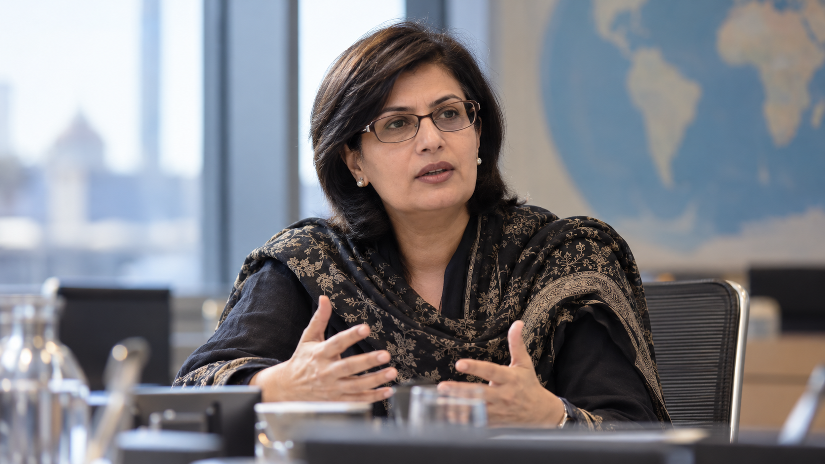 Sania Nishtar in a global health commission meeting with country reports and subdued conference lighting